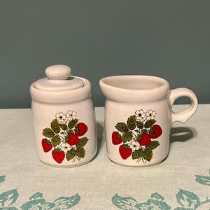 May include: A set of three ceramic mugs with a speckled, matte finish. The mugs are in shades of cream, light gray, and dark gray. Each mug has a simple, minimalist design, perfect for coffee or tea.