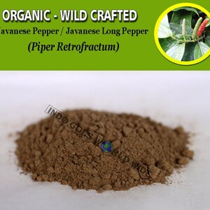 Puede incluir: Primer plano de un mont&oacute;n de pimienta larga de Java molida, tambi&eacute;n conocida como Piper Retrofractum. La pimienta es de color marr&oacute;n oscuro y tiene una textura gruesa. El texto "INDO GOES WORLD WIDE" es visible en la esquina inferior derecha de la imagen.
