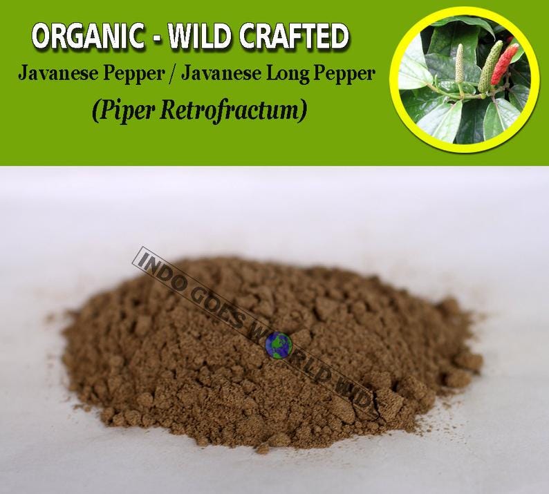 Puede incluir: Primer plano de un mont&oacute;n de pimienta larga de Java molida, tambi&eacute;n conocida como Piper Retrofractum. La pimienta es de color marr&oacute;n oscuro y tiene una textura gruesa. El texto "INDO GOES WORLD WIDE" es visible en la esquina inferior derecha de la imagen.