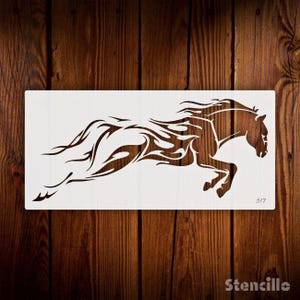 May include: A white stencil of a horse running with a flame design. The stencil is on a wooden background.