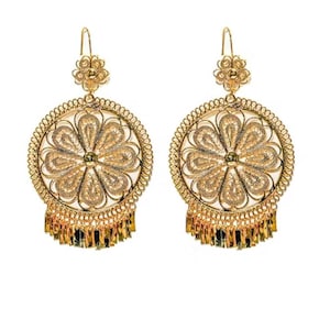 以下が含まれることがあります： 金色の透かし細工のイヤリングのペア。各イヤリングは、花の模様、ビーズの縁取り、小さな金色のビーズのフリンジを備えた円形デザインです。イヤリングはフック留めと上部の小さな花のディテールを備えています。