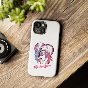May include: White phone case with a pink heart and a cartoon image of Harley Quinn with the text "Harley Quinn" in pink letters.