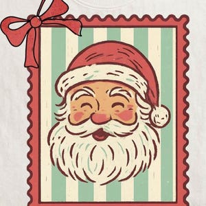 May include: A white t-shirt featuring a vintage-style illustration of Santa Claus. The design is framed within a red postage stamp border, with a red bow at the top left. Santa is depicted with a rosy face, white beard, and a red hat.
