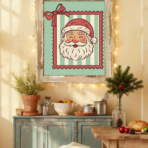 May include: A framed Christmas print featuring Santa Claus's face on a postage stamp design. The artwork has a red and white color scheme with a light blue background and is set in a rustic wooden frame. The image is part of a festive holiday decor.