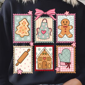 May include: Black sweatshirt with a festive design of gingerbread-themed postage stamps. The stamps feature a gingerbread tree, apron, gingerbread man, rolling pin, gingerbread house, and oven mitt. A pink bow and stars complete the design.