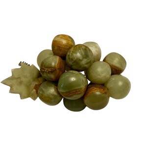 May include: A collection of green and brown marble spheres, some with a striped pattern, are clustered together. A light green, star-shaped object is on the left side of the cluster. The spheres vary in size and have a polished appearance.