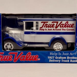 May include: A die-cast model of a 1927 Graham Brothers Delivery Truck Bank, in a blue and white box. The truck is white with blue accents and the True Value logo. The box reads "Help Is Just Around The Corner."