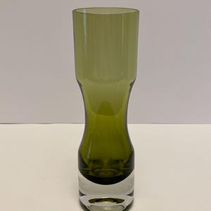 May include: A tall, green glass vase with a flared base and a clear glass bottom. The vase is made of thick glass and has a smooth, polished finish.
