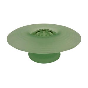 May include: A pale green glass flower frog. It has a wide, shallow, saucer-like top and a rounded base. The centre of the top has holes for arranging flower stems. The glass has a frosted appearance.
