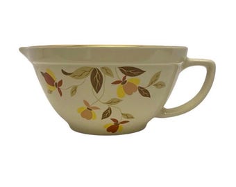 May include: A vintage white ceramic mixing bowl with a gold rim and a floral pattern in shades of brown, yellow, and orange.