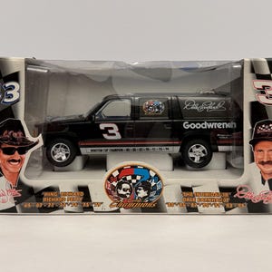 Peut inclure: Un modèle réduit de SUV noir avec le numéro 3 sur le côté, présenté dans une boîte en plastique transparente. La boîte présente des images de Richard Petty et Dale Earnhardt, avec le texte "Winston Cup Champion" et "Goodwrench".