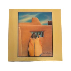 May include: A framed print depicting a person in an orange garment looking out a barred window of a Southwestern adobe building. The artwork is set against a blue sky and is signed by the artist.