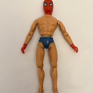 Puede incluir: Figura de acci&oacute;n vintage de un superh&eacute;roe con m&aacute;scara y guantes rojos, y calzoncillos azules. La figura tiene articulaciones y un tono de piel bronceado. La m&aacute;scara presenta formas de ojos blancos. La figura est&aacute; de pie con los brazos extendidos.