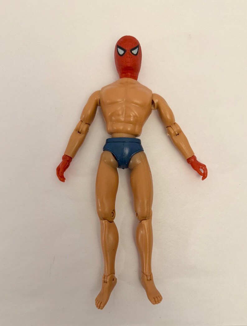 Puede incluir: Figura de acci&oacute;n vintage de un superh&eacute;roe con m&aacute;scara y guantes rojos, y calzoncillos azules. La figura tiene articulaciones y un tono de piel bronceado. La m&aacute;scara presenta formas de ojos blancos. La figura est&aacute; de pie con los brazos extendidos.