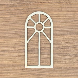 May include: A light-colored wooden cutout in the shape of an arched window frame. The design features a central circular pane surrounded by four radiating segments, with two vertical rectangular panes below, all enclosed within a rounded arch frame.