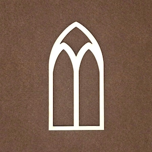 May include: A light-colored, flat, wooden cutout shaped like a pointed arch window. The frame features a central vertical divider and a decorative Y-shaped arch at the top, creating two distinct vertical openings within the overall structure.