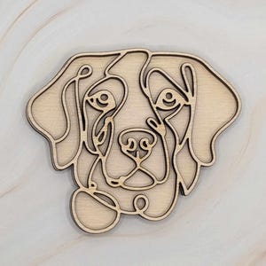 May include: A wooden cutout of a dog's head in a line art style. The dog has floppy ears and a sweet expression.