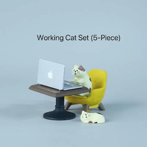Peut inclure: Un ensemble de 5 pièces "Working Cat". L'ensemble comprend un ordinateur portable miniature sur une table marron, un fauteuil jaune et deux figurines de chat. Un chat est assis dans la chaise et un autre est allongé. Le texte "Working Cat Set (5-Piece)" est au-dessus.