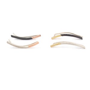 May include: Four pairs of curved bar earrings in various color combinations. One pair is silver with a copper accent, another is black with a copper accent. The other two pairs are silver and gold, and black and gold. The earrings are on a white background.
