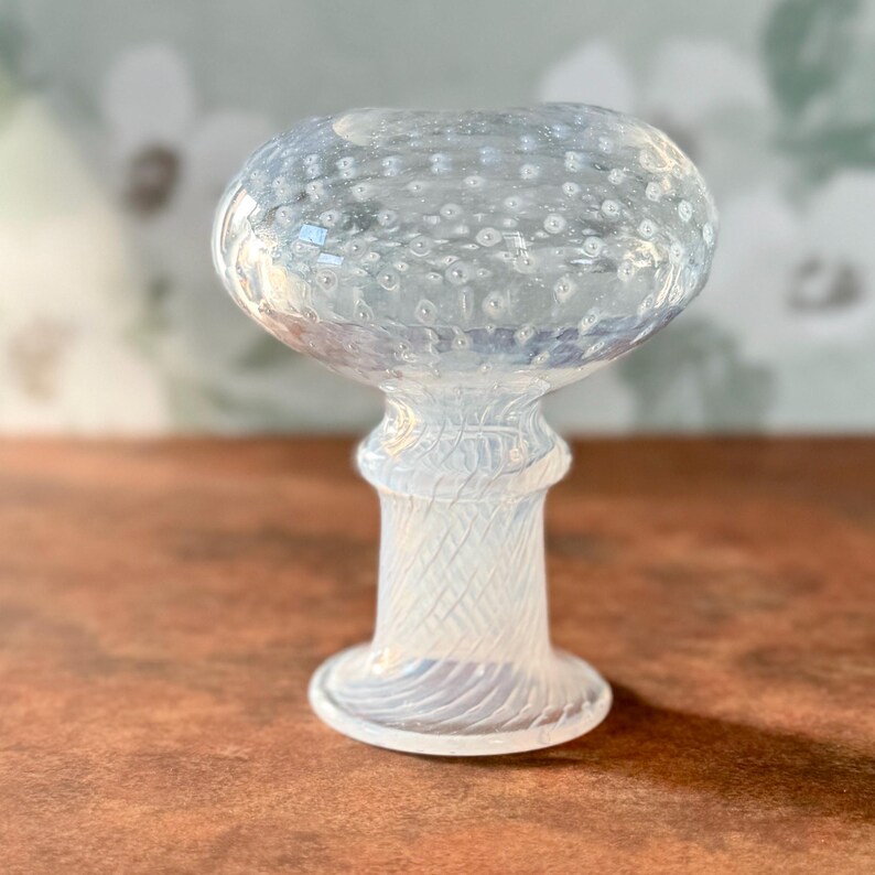 Op de afbeelding: Een heldere glazen vaas met een kenmerkende vorm, met een bolvormige bovenkant en een patroonsteel. De vaas is ontworpen voor decoratieve doeleinden, met een bubbelachtige textuur. Hoogte ongeveer 15 cm.