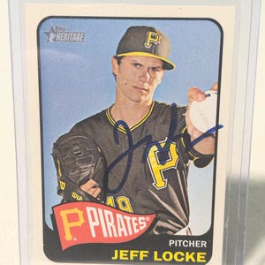 Puede incluir: Tarjeta de béisbol de Jeff Locke de los Piratas de Pittsburgh. La tarjeta tiene un diseño vintage con el logo de los Piratas en rojo y amarillo. El jugador viste un uniforme negro y amarillo y una gorra con la letra "P". La tarjeta está en una funda protectora.