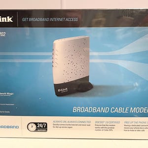 May include: A white D-Link DCM-202 broadband cable modem with a black base. The box features the text "GET BROADBAND INTERNET ACCESS" and "BROADBAND CABLE MODEM".