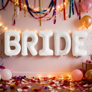 May include: White balloon letters spelling "BRIDE" are suspended against a pink wall, decorated with colorful streamers, string lights, and balloons. The floor is scattered with confetti and rose petals, creating a festive atmosphere.