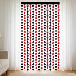 May include: A decorative curtain featuring a repeating pattern of playing card suits and dice in red and black. The curtain hangs in front of a white sheer curtain, creating a layered effect. The design is suitable for a game room or themed space.