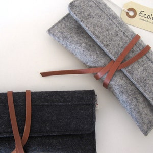 Two deluxe glasses cases in black and silver gray soft merino wool felt, adorned with a distinctive leather wrap-around closure