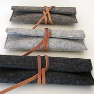 Three soft wool felt reading glass cases in black silver and natural gray featuring a unique leather wrap around closure