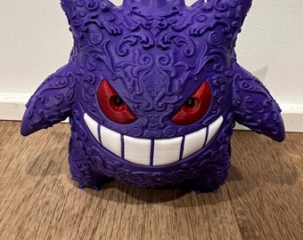 May include: A purple 3D printed Gengar figurine with intricate details and red eyes. The figurine is posed with a wide grin and is standing on a wooden surface.