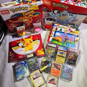 Puede incluir: Una colecci&oacute;n de merchandising de Pok&eacute;mon, que incluye sets de construcci&oacute;n Mega Construx, cartas coleccionables y peque&ntilde;as figuras. Los sets presentan a Pikachu y otros personajes. Las cartas est&aacute;n en fundas protectoras.