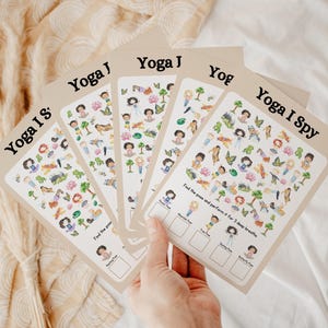 Può includere: Cinque carte stampabili a tema yoga. Ogni carta presenta un'illustrazione colorata di pose yoga e altri oggetti. Le carte riportano il testo "Yoga I Spy" e istruzioni per trovare le pose ed eseguirle per tre respiri profondi.