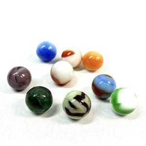 May include: A collection of nine glass marbles in various colors and patterns. The set includes solid blue, orange, and purple spheres, alongside white marbles with brown, green, or blue swirls, and a dark green marble with subtle internal veining.