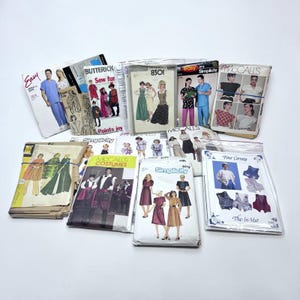 May include: A collection of assorted sewing patterns from brands including Simplicity, McCall's, and Butterick. The rectangular paper envelopes feature printed illustrations of various garments, including vests, dresses, and scrubs, with visible text labels.