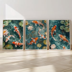 Op de afbeelding: Drie ingelijste prints van koi-karpers die zwemmen in een vijver met waterlelies. De vissen zijn oranje en wit met zwarte markeringen. Het water is blauwgroen.