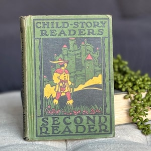May include: A vintage green book titled "Child-Story Readers Second Reader" with an illustration of a person in a red and yellow costume walking towards a green castle.
