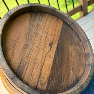 May include: A wooden bucket with a dark brown stain and a metal handle. The bucket is made of wood slats and has a round shape.