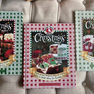 May include: Three Gooseberry Patch Christmas cookbooks. Book 3 has a jar of preserves on the cover. Book 4 features a cake on a stand. Book 5 shows a bowl of food. All books have a green and red plaid border.