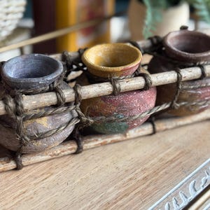 May include: A set of three ceramic canisters with lids. The canisters are white with a blue floral pattern. The largest canister is 8 inches tall, the medium is 7 inches, and the smallest is 6 inches.