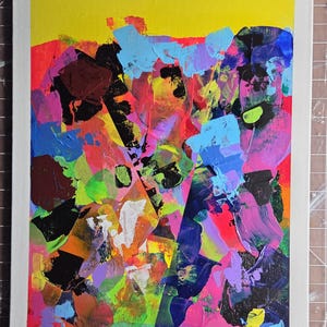 May include: Abstract acrylic painting on canvas with a white border. The artwork features bold brushstrokes in vibrant colours including yellow, blue, pink, purple, and black. The artist's signature is in the bottom right corner.