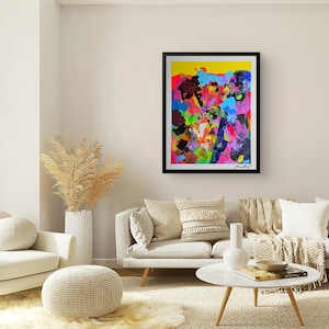 May include: Abstract art print in a black frame. The artwork features a vibrant mix of colours, including yellow, pink, blue, and green, with bold brushstrokes. The painting is signed in the bottom right corner. The artwork is displayed in a living room setting.