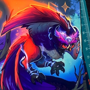 May include: A stack of art prints featuring a stylized owl-like creature with vibrant colors. The artwork showcases a creature with red, purple, and orange hues, set against a backdrop of a starry night and fiery sky. The creature has a mask and detailed feathers.