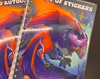 May include: Two spiral-bound notebooks featuring a vibrant illustration of a mythical bird-like creature with orange, purple, and blue feathers. The cover on the right displays the text "NEST OF STICKERS" in white, while the left cover shows "NID D'AUTOCO".