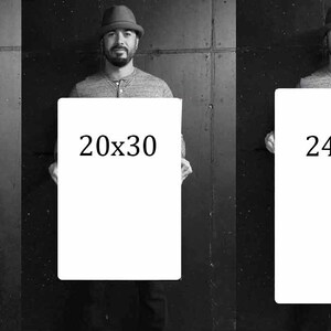 May include: Five different sizes of blank canvases are held by a person wearing a hat. The canvases are labeled with their dimensions in inches: 10x15, 16x24, 20x30, 24x36, and 28x42.