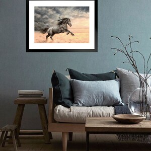 May include: A framed painting of a spotted horse running through a field with a stormy sky in the background.