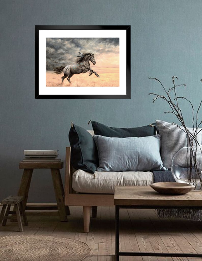 May include: A framed painting of a spotted horse running through a field with a stormy sky in the background.