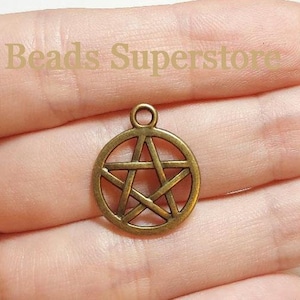May include: A circular bronze-toned metal charm featuring a five-pointed star pentagram design enclosed within a ring, with a small loop at the top for attachment. The text Beads Superstore is visible in the background.