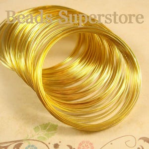 May include: A collection of thin, circular gold-colored wire loops arranged in a stack. The text "Beads Superstore" is visible across the top portion of the image. The wire has a metallic finish and a consistent, smooth, rounded cross-section.
