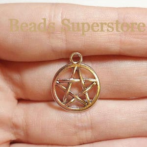 May include: A gold-toned metal pentagram charm featuring a circular outer frame and a five-pointed star design in the center with a small loop at the top for attachment. The text Beads Superstore is visible in the background.
